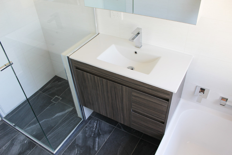 Inspiration for a small modern kids bathroom in Perth with furniture-like cabinets, brown cabinets, a drop-in tub, a corner shower, white tile, ceramic tile, white walls, porcelain floors, an integrated sink, solid surface benchtops, black floor, a hinged shower door and yellow benchtops.
