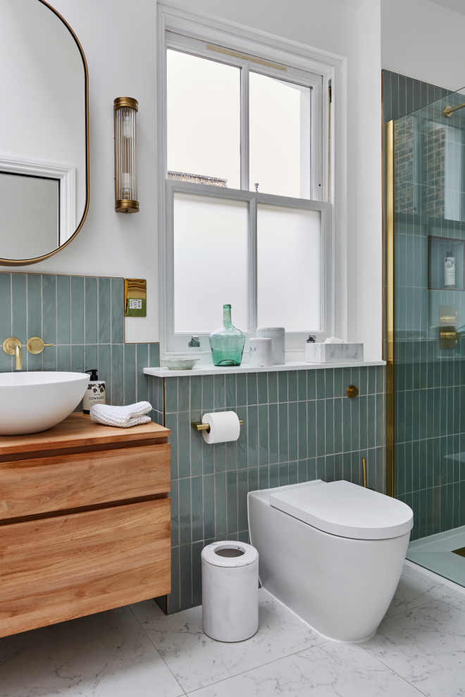 Medium sized classic bathroom in London with a freestanding bath, a walk-in shower, a wall mounted toilet, green tiles, ceramic tiles, white walls, marble flooring, a vessel sink, wooden worktops, white floors, a hinged door, brown worktops, a wall niche, a single sink, a floating vanity unit and a vaulted ceiling.