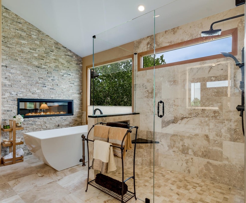 Inspiration for a large mediterranean master bathroom in Denver with glass-front cabinets, beige cabinets, a freestanding tub, a curbless shower, beige tile, travertine, beige walls, travertine floors, an undermount sink, quartzite benchtops, beige floor and a hinged shower door.