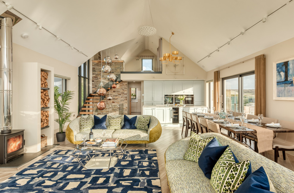 This is an example of a large beach style loft-style living room in Cornwall with beige walls, laminate floors, a wood stove and a plaster fireplace surround.