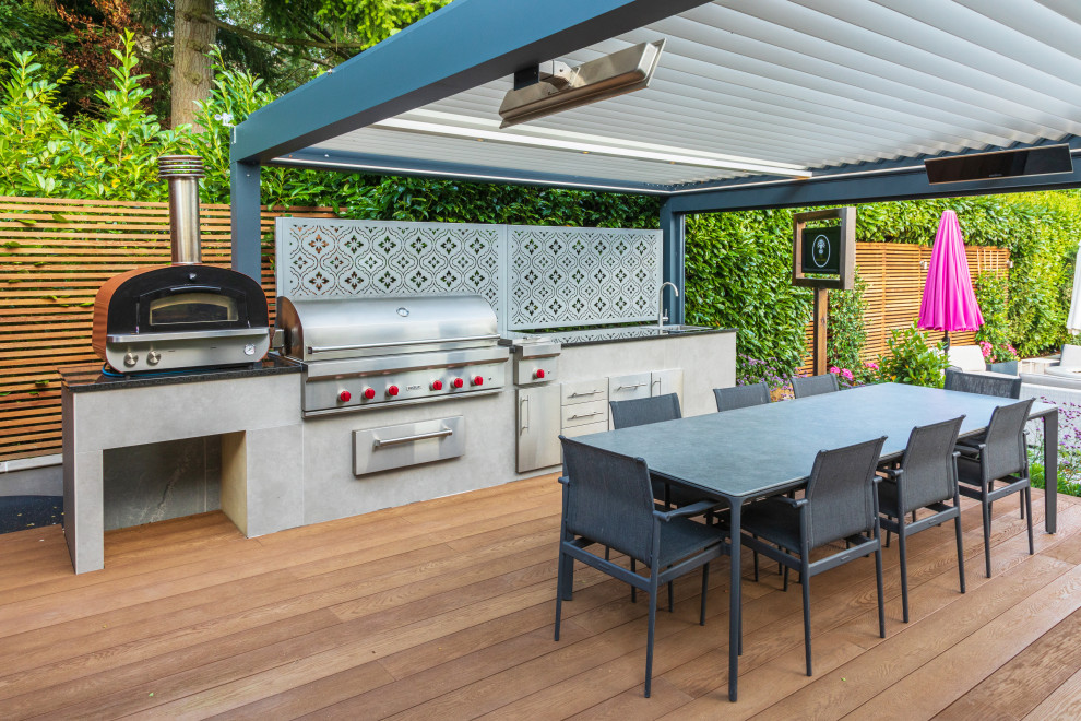 Photo of a mid-sized contemporary backyard deck in Buckinghamshire with a pergola and metal railing.