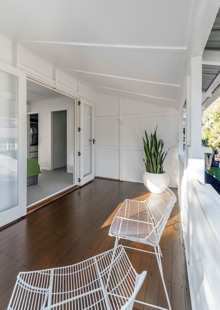 Inspiration for a contemporary balcony in Brisbane with a roof extension and wood railing.