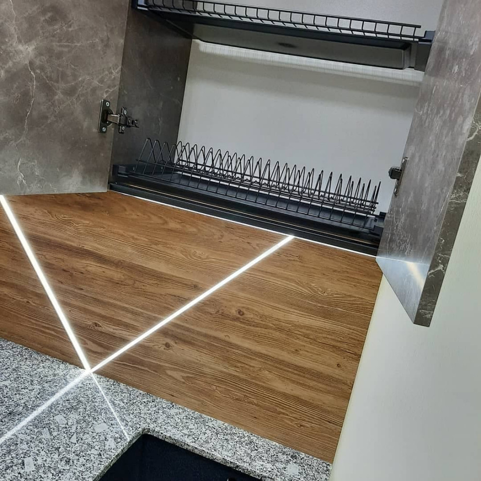 Inredning av ett modernt litet grå linjärt grått kök med öppen planlösning, med en integrerad diskho, släta luckor, grå skåp, granitbänkskiva, brunt stänkskydd, stänkskydd i trä, svarta vitvaror, klinkergolv i keramik och vitt golv