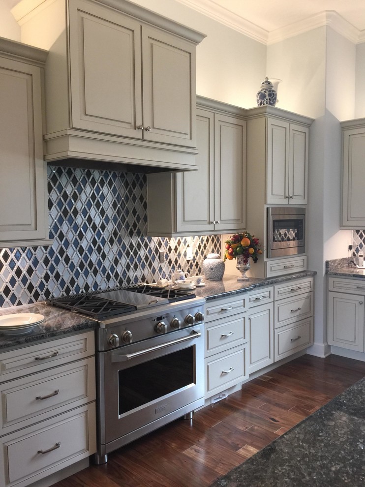 Mid-sized transitional u-shaped eat-in kitchen in Orlando with a double-bowl sink, raised-panel cabinets, yellow cabinets, quartzite benchtops, multi-coloured splashback, mosaic tile splashback, stainless steel appliances, dark hardwood floors, with island and brown floor.