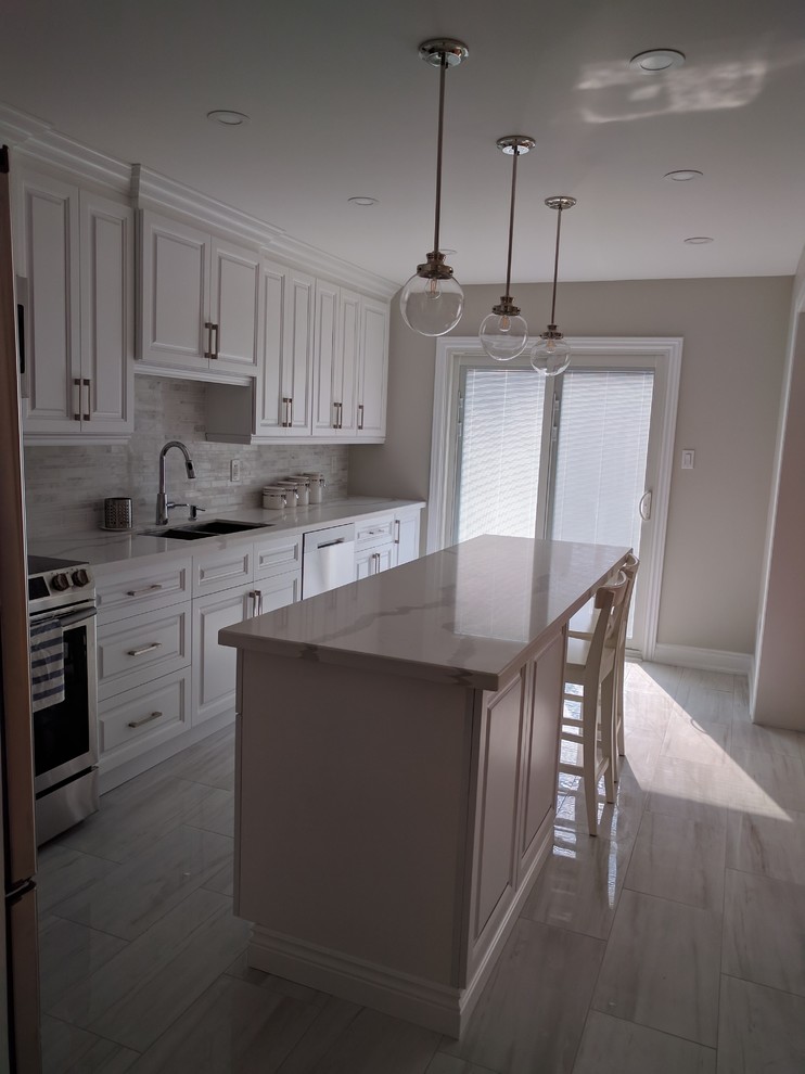 Example of a mid-sized transitional l-shaped kitchen design in Toronto with an undermount sink, raised-panel cabinets, white cabinets, stainless steel appliances and an island