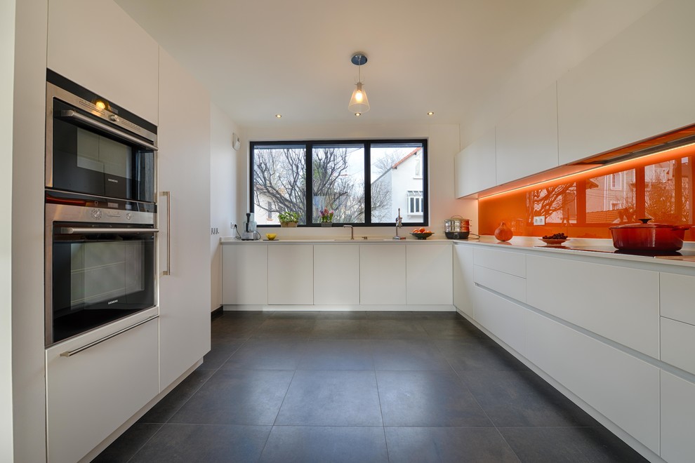 This is an example of a contemporary kitchen in Paris with orange splashback.