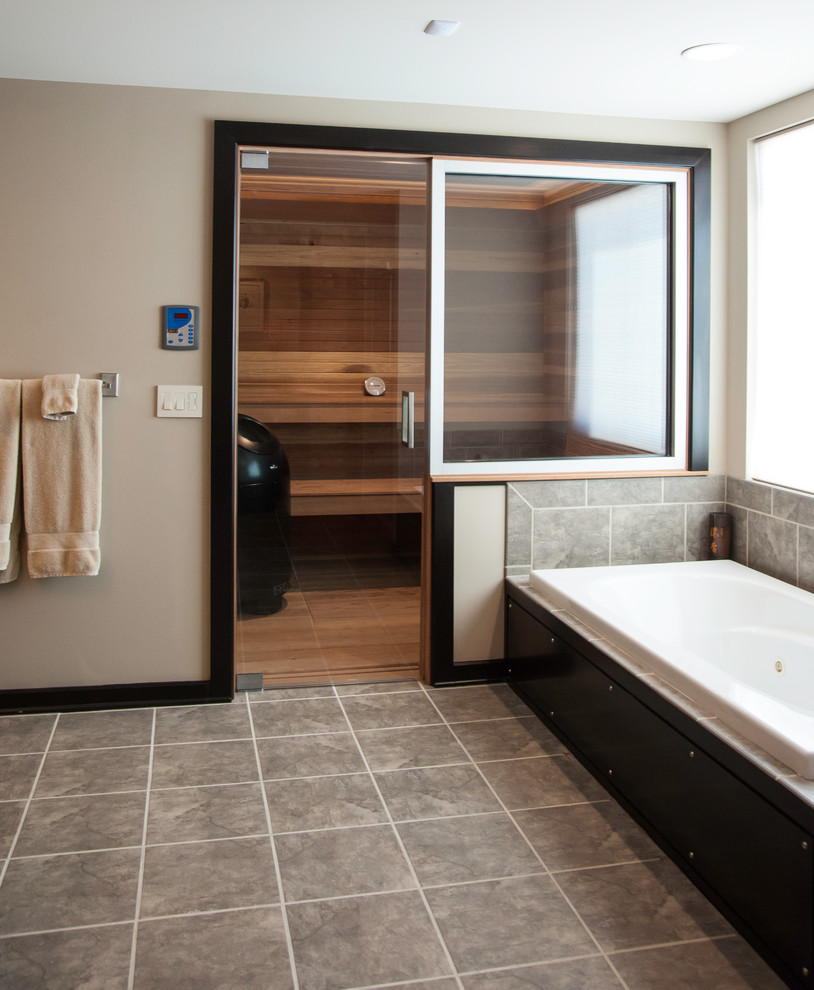 Large modern master bathroom in Wichita with an undermount sink, flat-panel cabinets, dark wood cabinets, granite benchtops, an alcove tub, an alcove shower, gray tile, porcelain tile, beige walls, porcelain floors, grey floor and a hinged shower door.