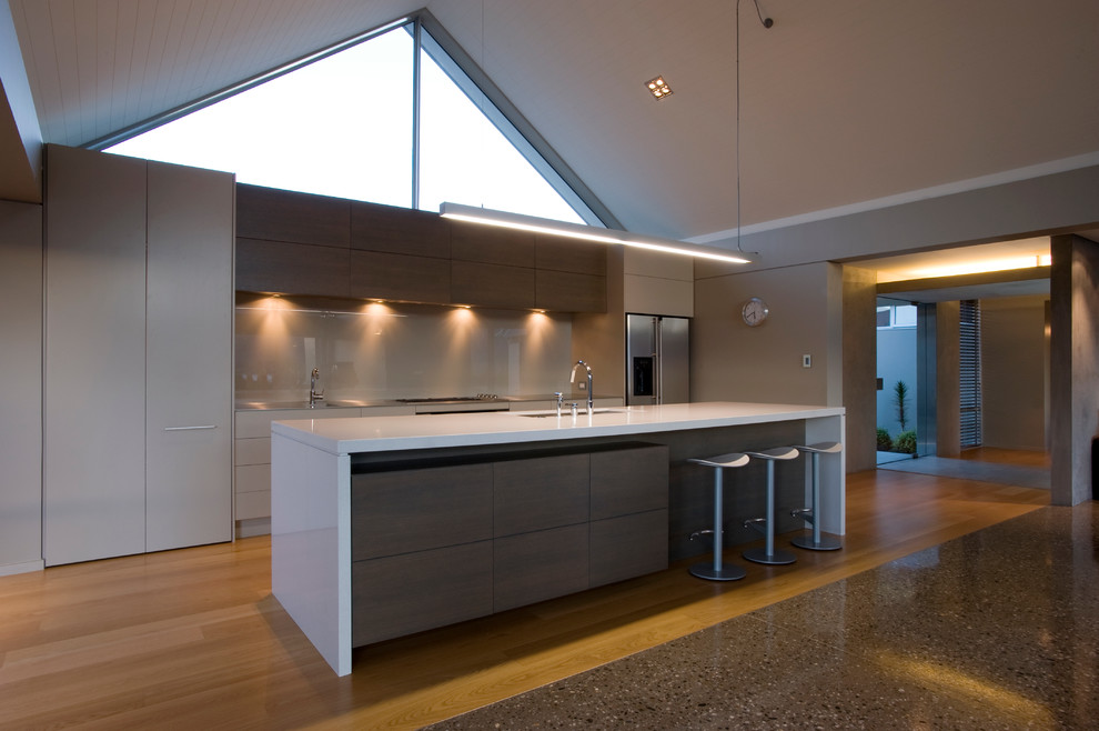 Photo of a large contemporary open plan kitchen in Christchurch with an undermount sink, beaded inset cabinets, beige cabinets, quartz benchtops, beige splashback, glass sheet splashback, light hardwood floors and with island.