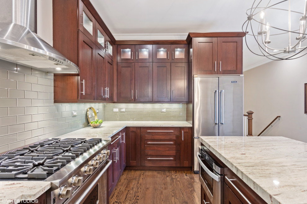 Inspiration for a transitional u-shaped medium tone wood floor and brown floor open concept kitchen remodel in Chicago with an undermount sink, shaker cabinets, dark wood cabinets, granite countertops, gray backsplash, ceramic backsplash, stainless steel appliances and an island