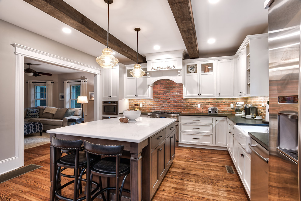 Inspiration for a large country l-shaped eat-in kitchen in New York with a farmhouse sink, beaded inset cabinets, white cabinets, granite benchtops, brick splashback, stainless steel appliances, with island, brown floor, black benchtop, red splashback and painted wood floors.