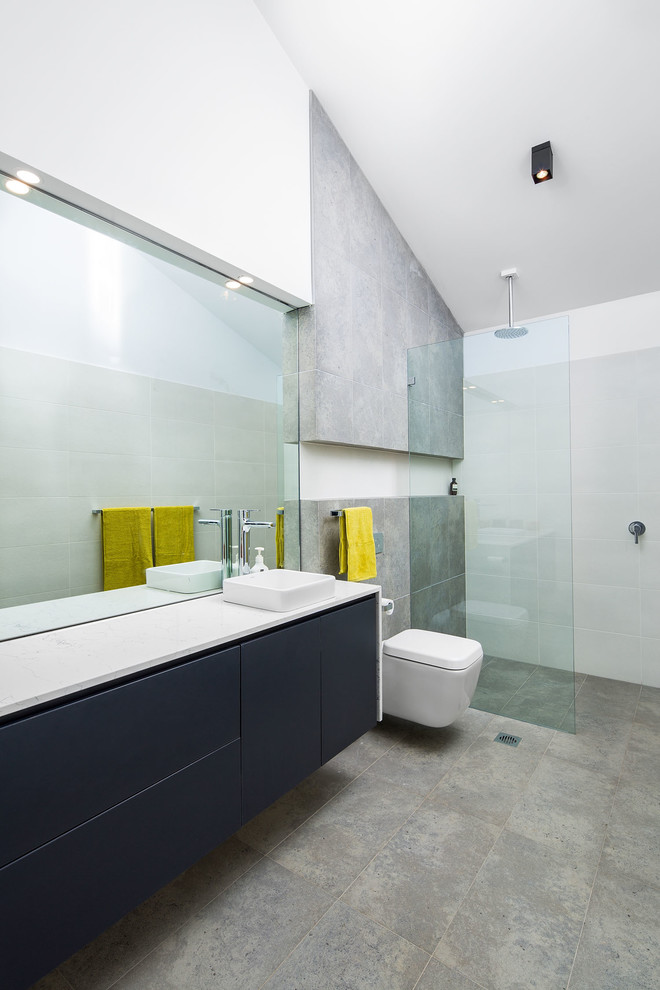Large contemporary 3/4 bathroom in Melbourne with a vessel sink, flat-panel cabinets, blue cabinets, an open shower, a wall-mount toilet, gray tile and an open shower.