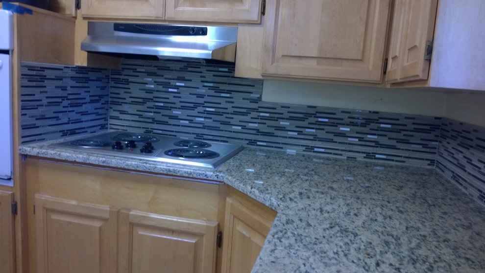Example of a l-shaped eat-in kitchen design in Seattle with light wood cabinets, granite countertops, glass tile backsplash and stainless steel appliances