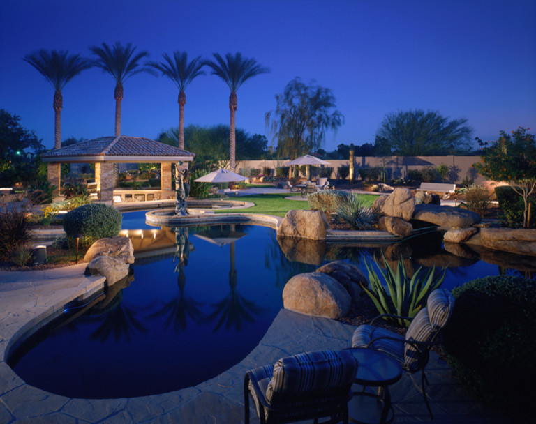 Expansive traditional backyard rectangular lap pool in Phoenix with a water feature and natural stone pavers.