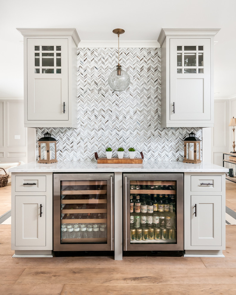 Mid-sized beach style single-wall home bar in Atlanta with no sink, shaker cabinets, grey cabinets, multi-coloured splashback and light hardwood floors.