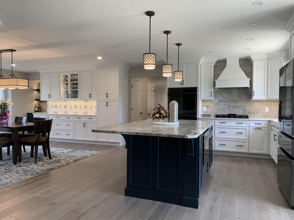 Eat-in kitchen - large transitional l-shaped vinyl floor and gray floor eat-in kitchen idea with an undermount sink, recessed-panel cabinets, white cabinets, quartz countertops, gray backsplash, ceramic backsplash, stainless steel appliances, an island and white countertops