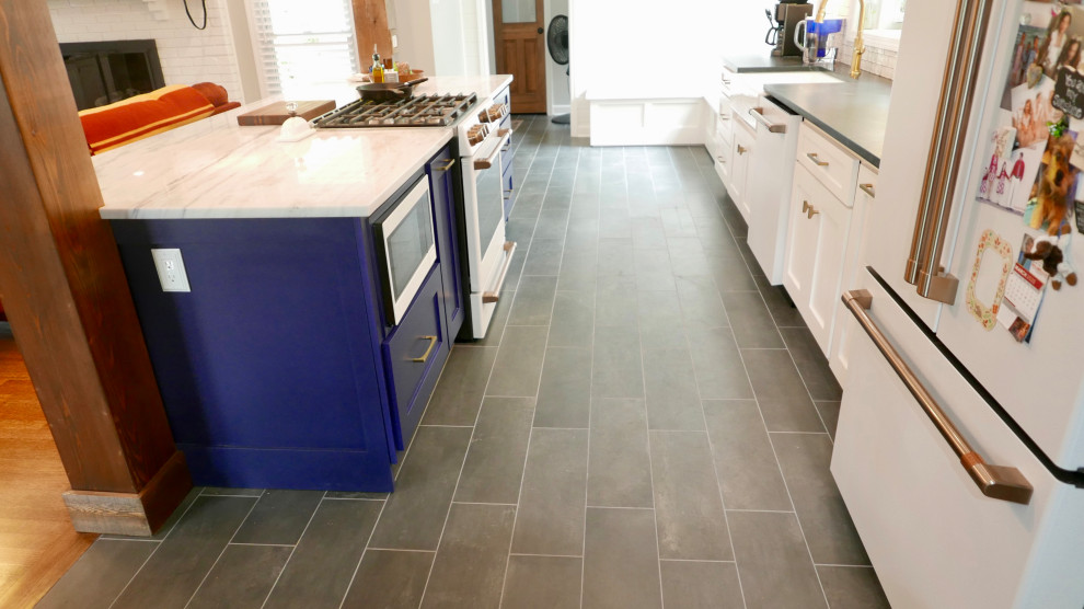 Inspiration for a mid-sized transitional galley porcelain tile and black floor eat-in kitchen remodel with a farmhouse sink, shaker cabinets, white cabinets, marble countertops, white backsplash, subway tile backsplash, white appliances, an island and multicolored countertops