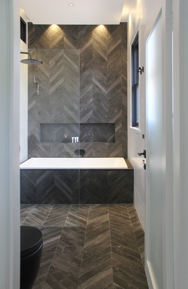 Small contemporary master bathroom in Sydney with flat-panel cabinets, medium wood cabinets, a drop-in tub, an open shower, a wall-mount toilet, gray tile, porcelain tile, white walls, porcelain floors, a vessel sink, laminate benchtops, grey floor and an open shower.