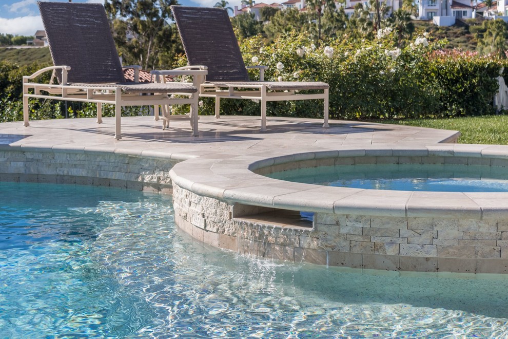 Inspiration for a large contemporary backyard custom-shaped pool in Orange County with a water feature and tile.