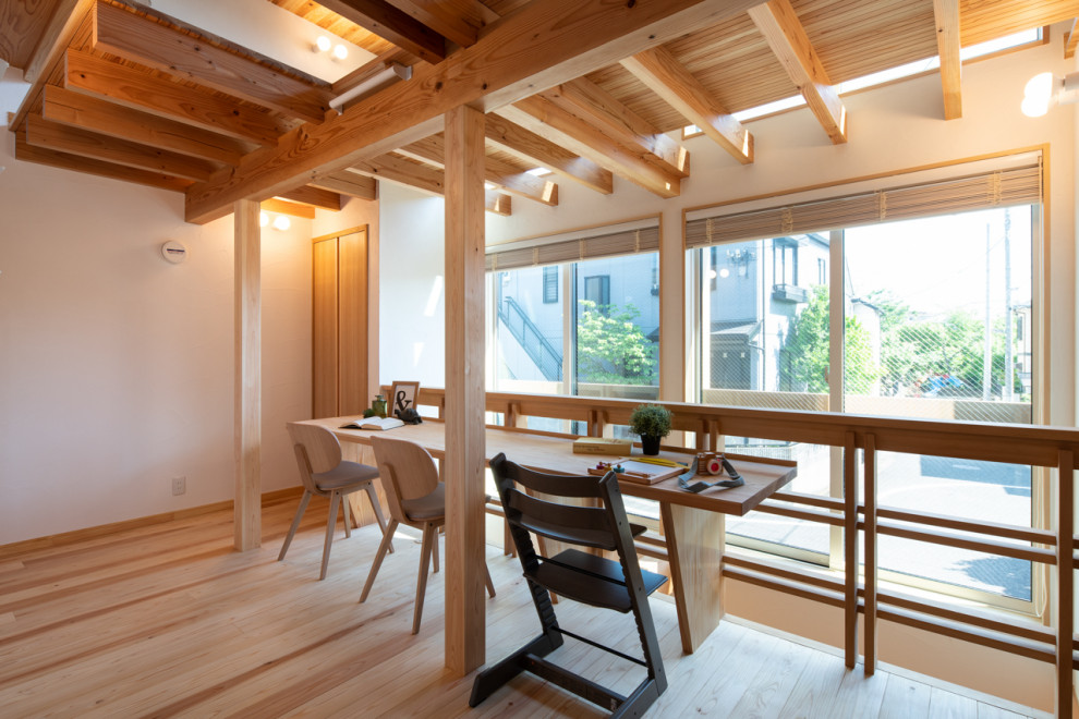 Asian home office in Tokyo with white walls, light hardwood floors, a built-in desk and beige floor.