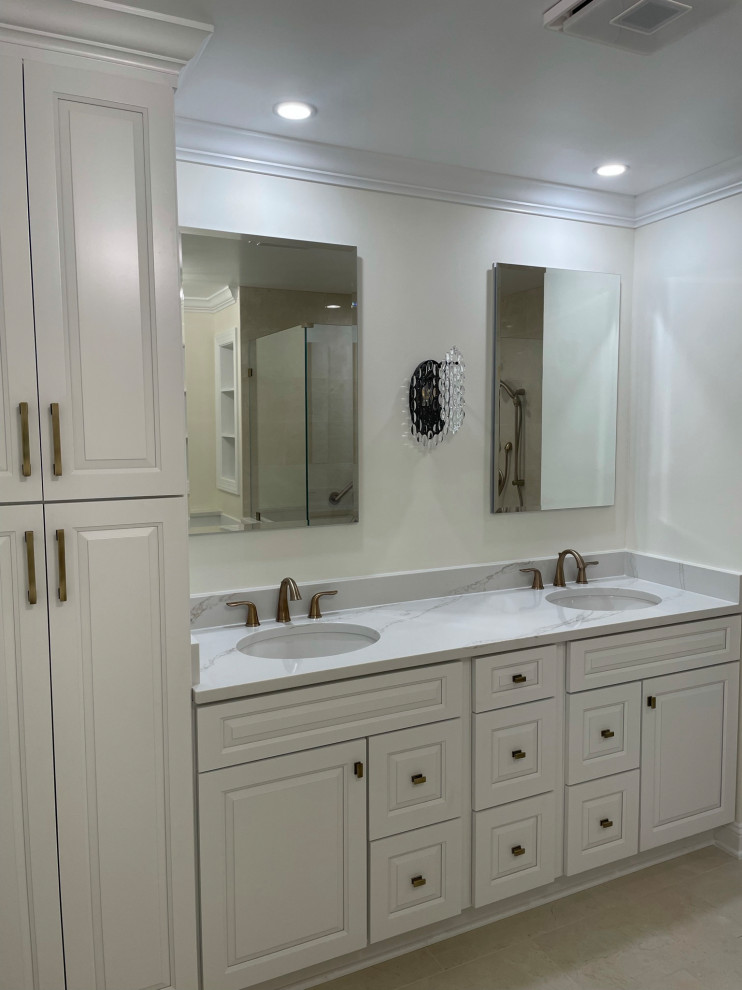 Inspiration for an expansive modern ensuite bathroom in DC Metro with freestanding cabinets, white cabinets, a corner shower, beige walls, travertine flooring, an integrated sink, beige floors, a hinged door, double sinks, a built in vanity unit, quartz worktops, white worktops and feature lighting.