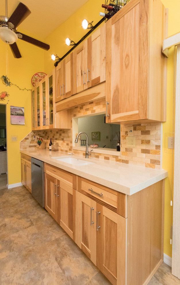 Photo of a small eclectic galley separate kitchen in Miami with a double-bowl sink, shaker cabinets, medium wood cabinets, quartz benchtops, brown splashback, stone tile splashback, stainless steel appliances, vinyl floors and brown floor.