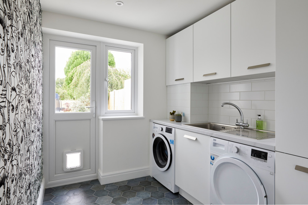 Inspiration for a mid-sized modern laundry room in Kent with an undermount sink, flat-panel cabinets, white cabinets, quartzite benchtops, blue splashback, glass sheet splashback, medium hardwood floors, brown floor and white benchtop.