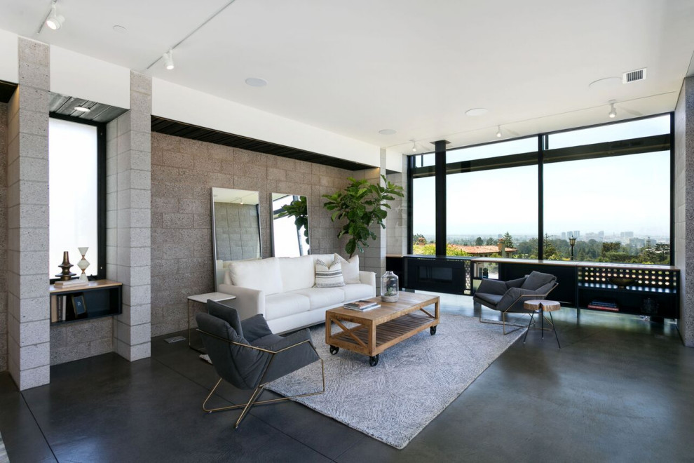 Idée de décoration pour un grand salon design ouvert avec un mur gris, sol en béton ciré, cheminée suspendue, un manteau de cheminée en métal, un sol gris et un mur en parement de brique.