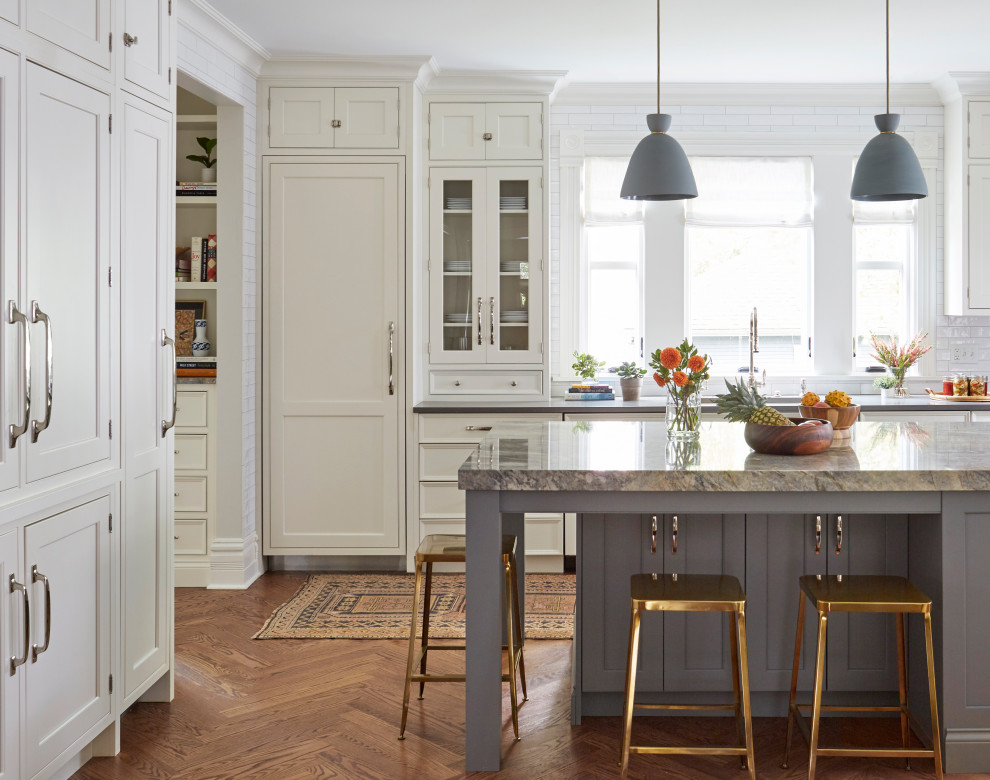 Inspiration for a transitional l-shaped kitchen in Chicago with an undermount sink, recessed-panel cabinets, white cabinets, panelled appliances, medium hardwood floors, with island, brown floor and grey benchtop.