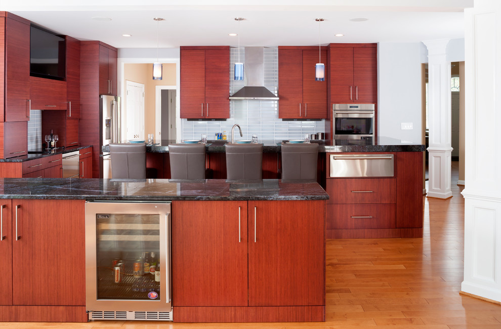 Inspiration for a large contemporary l-shaped eat-in kitchen in DC Metro with medium wood cabinets, granite benchtops, grey splashback, subway tile splashback, stainless steel appliances, light hardwood floors and multiple islands.