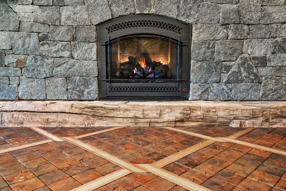 Large mountain style open concept medium tone wood floor and brown floor home design photo with gray walls, a standard fireplace, a stone fireplace and a wall-mounted tv