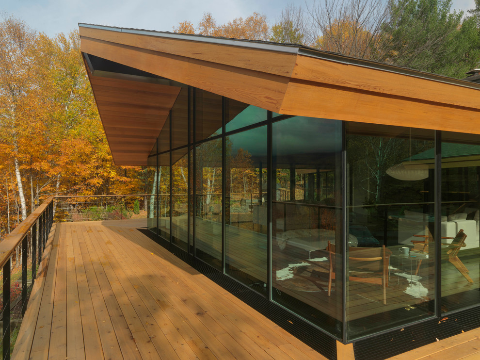 This is an example of a large contemporary side yard deck in Burlington with a roof extension.