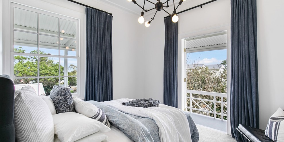 This is an example of a large traditional guest bedroom in Auckland with white walls, carpet and grey floor.