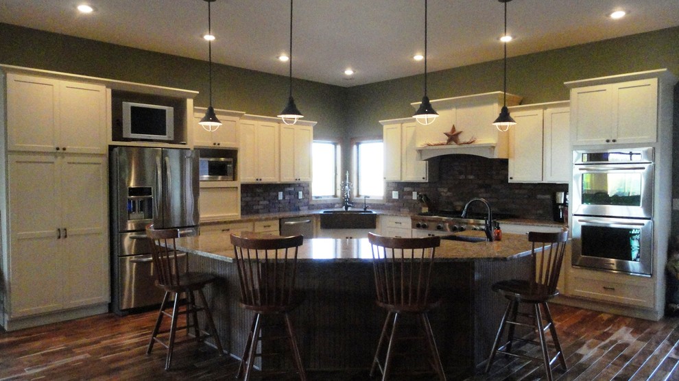 Open concept kitchen - large transitional l-shaped dark wood floor and brown floor open concept kitchen idea with a farmhouse sink, white cabinets, granite countertops, stainless steel appliances, green walls, an island, shaker cabinets, brown backsplash and stone tile backsplash