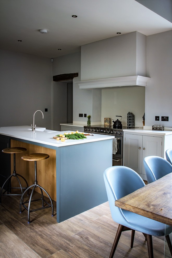 Photo of a mid-sized contemporary galley open plan kitchen in Other with a farmhouse sink, shaker cabinets, white cabinets, quartz benchtops, white splashback, glass sheet splashback, black appliances and with island.