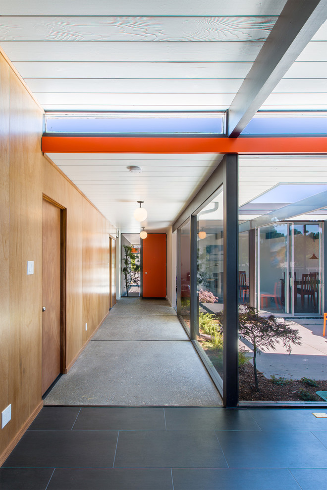 This is an example of a midcentury entryway in San Francisco with a single front door and an orange front door.