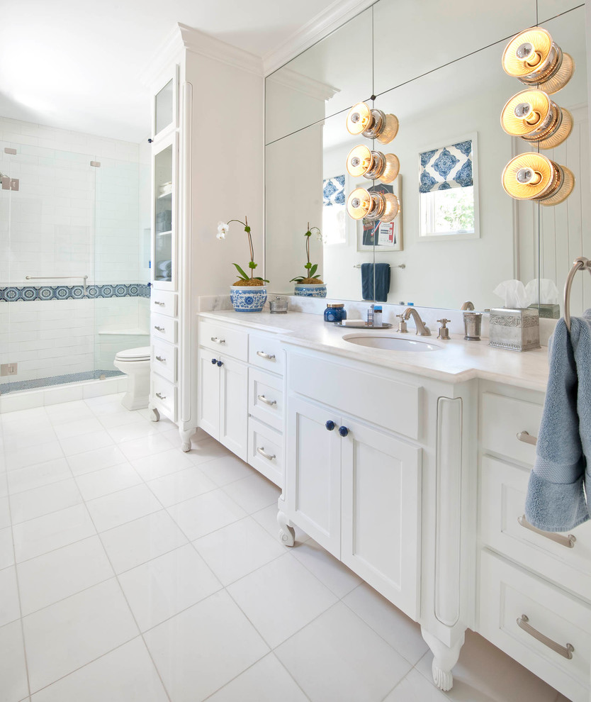 This is an example of a mediterranean bathroom in San Diego with an undermount sink, white cabinets, white walls and marble floors.