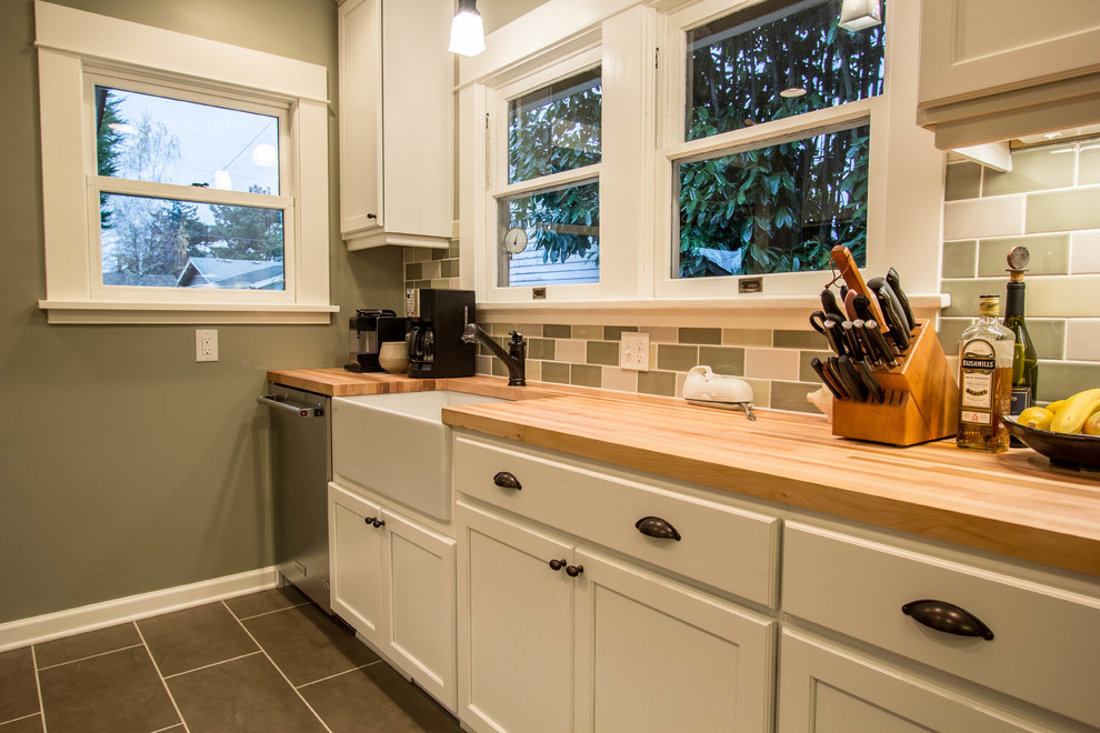 Photo of a small traditional kitchen in Portland with a farmhouse sink, recessed-panel cabinets, white cabinets, wood benchtops, ceramic splashback, stainless steel appliances, porcelain floors and no island.