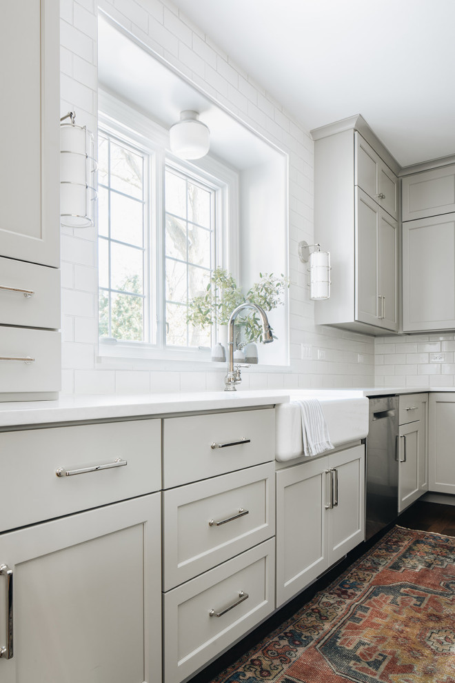 Example of a mid-sized transitional dark wood floor eat-in kitchen design in Chicago with a farmhouse sink, shaker cabinets, gray cabinets, quartz countertops, white backsplash, ceramic backsplash, paneled appliances, an island and white countertops