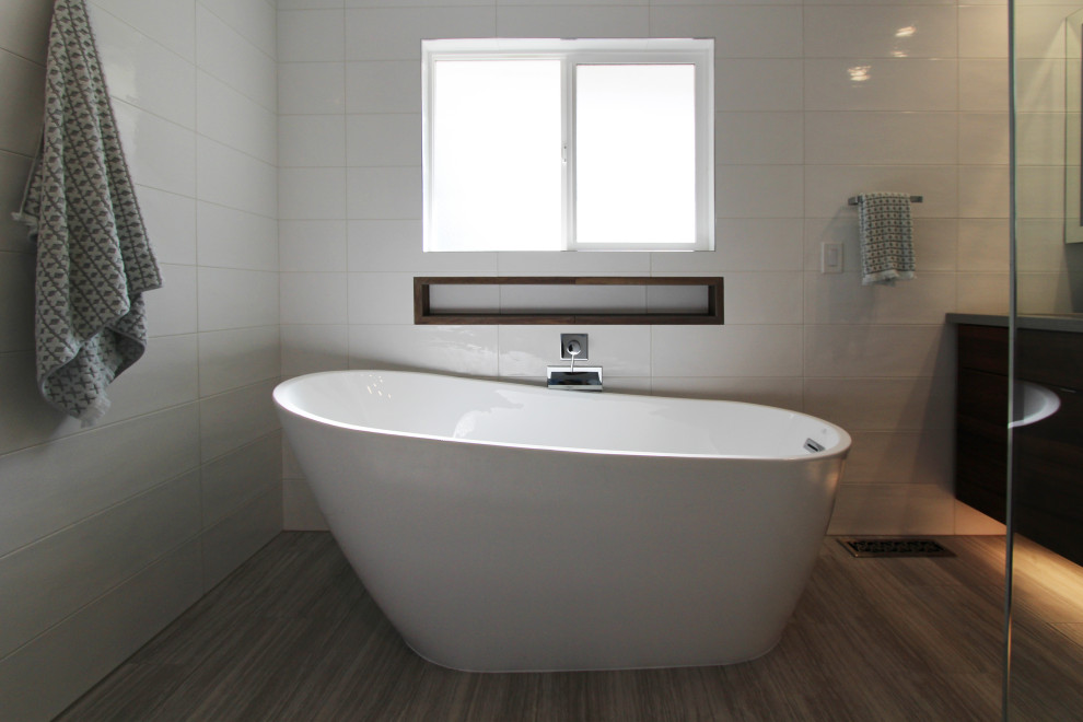 Large transitional master white tile and ceramic tile porcelain tile, gray floor and double-sink freestanding bathtub photo with flat-panel cabinets, dark wood cabinets, a one-piece toilet, white walls, an undermount sink, quartz countertops, gray countertops, a niche and a floating vanity