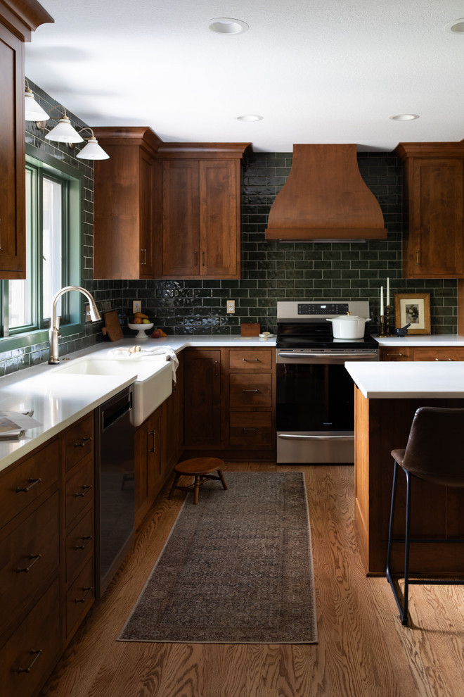 Mid-sized transitional l-shaped medium tone wood floor and brown floor kitchen pantry photo with a farmhouse sink, shaker cabinets, medium tone wood cabinets, quartz countertops, green backsplash, subway tile backsplash, stainless steel appliances, an island and white countertops