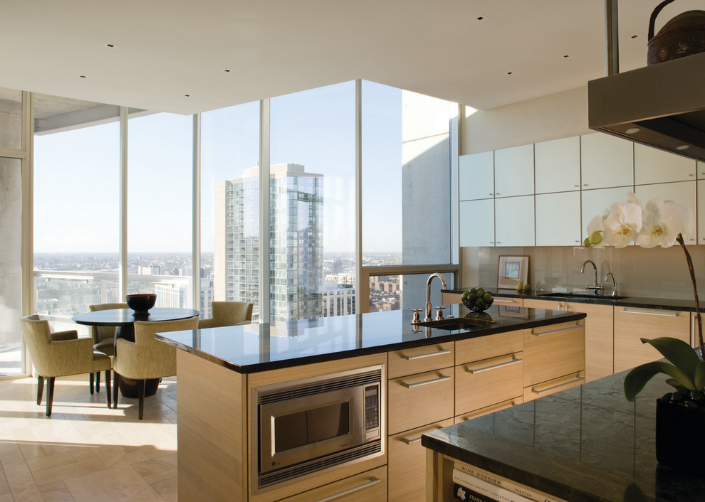 This is an example of a contemporary eat-in kitchen in Chicago with flat-panel cabinets, light wood cabinets, glass sheet splashback and beige splashback.