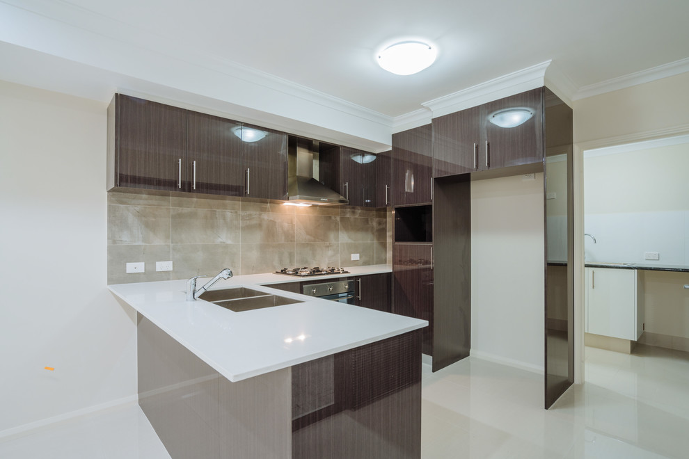 Photo of a mid-sized contemporary u-shaped open plan kitchen in Perth with a double-bowl sink, flat-panel cabinets, dark wood cabinets, quartz benchtops, brown splashback, stainless steel appliances and porcelain floors.