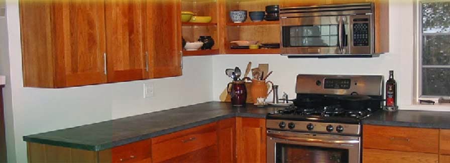 Mid-sized modern l-shaped eat-in kitchen in New York with flat-panel cabinets, medium wood cabinets, solid surface benchtops and stainless steel appliances.