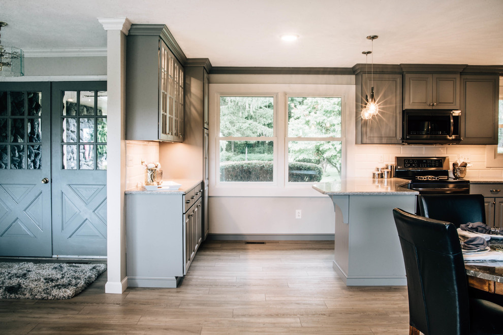 Inspiration for a mid-sized transitional u-shaped medium tone wood floor and brown floor eat-in kitchen remodel with a double-bowl sink, raised-panel cabinets, gray cabinets, granite countertops, white backsplash, ceramic backsplash, stainless steel appliances, a peninsula and gray countertops
