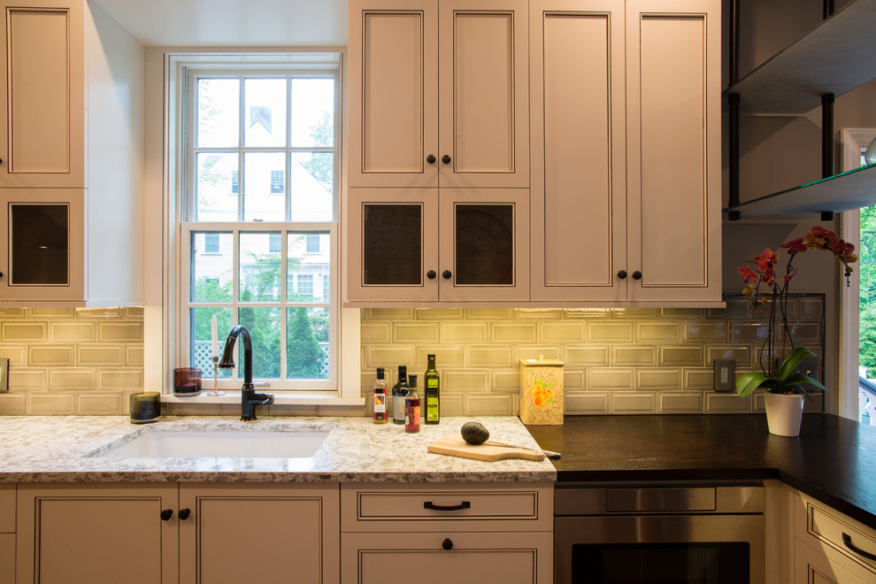 Eat-in kitchen - mid-sized transitional u-shaped medium tone wood floor eat-in kitchen idea in New York with an undermount sink, recessed-panel cabinets, white cabinets, subway tile backsplash, stainless steel appliances, a peninsula, granite countertops and beige backsplash