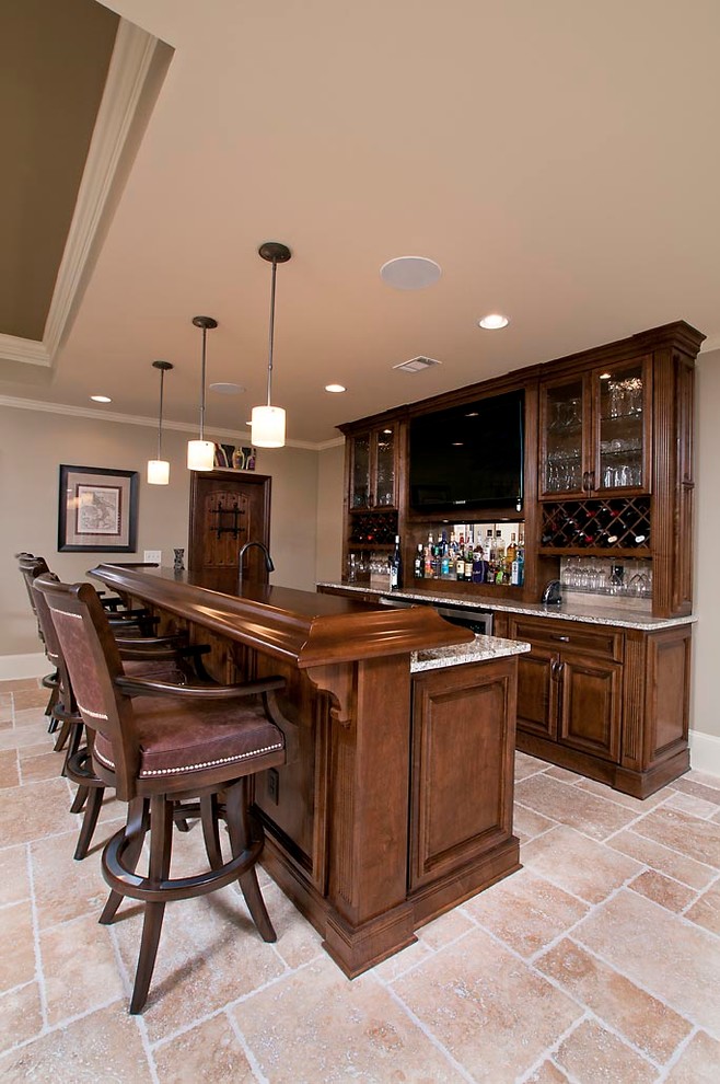 This is an example of a mid-sized traditional galley seated home bar in Atlanta with an undermount sink, raised-panel cabinets, medium wood cabinets, quartz benchtops, terra-cotta floors, beige floor and multi-coloured benchtop.