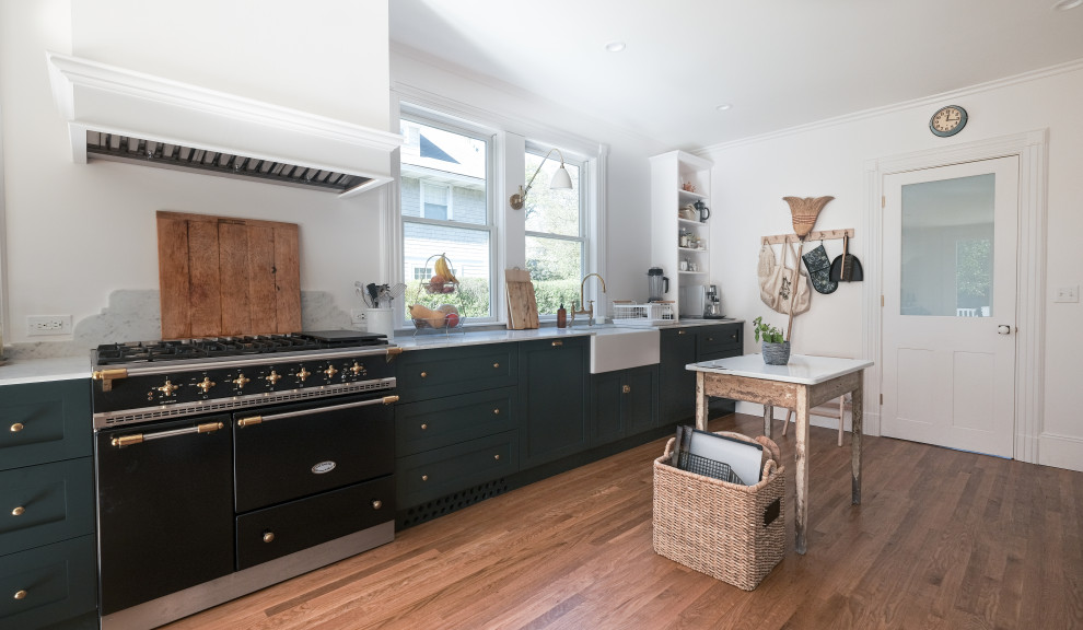 Inspiration for a large country galley separate kitchen in New York with a farmhouse sink, shaker cabinets, black appliances, with island, brown floor, white benchtop, black cabinets, marble benchtops and medium hardwood floors.