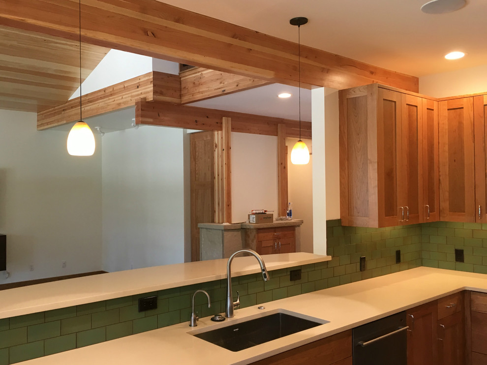 Transitional l-shaped home design photo in Denver with an undermount sink, recessed-panel cabinets, medium tone wood cabinets, quartz countertops, green backsplash, ceramic backsplash, stainless steel appliances and a peninsula
