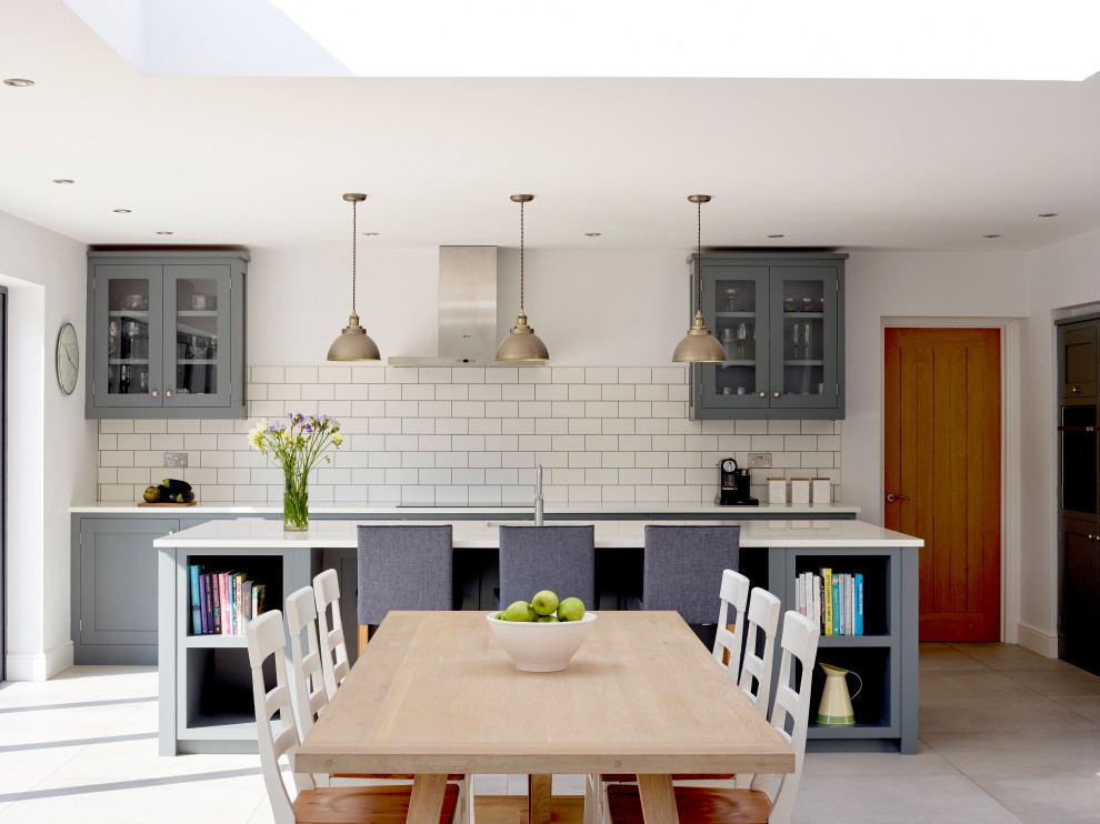 Photo of a medium sized traditional l-shaped open plan kitchen in Surrey with a built-in sink, shaker cabinets, grey cabinets, quartz worktops, white splashback, metro tiled splashback, stainless steel appliances, limestone flooring, an island and white worktops.