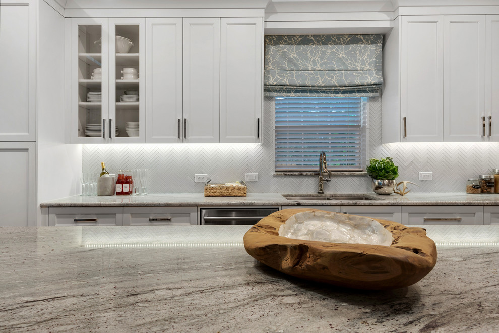 Inspiration for a mid-sized transitional l-shaped eat-in kitchen in Miami with an undermount sink, recessed-panel cabinets, white cabinets, granite benchtops, white splashback, glass tile splashback, stainless steel appliances, light hardwood floors and with island.